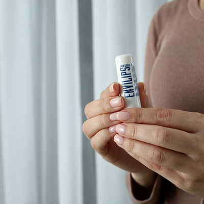 Mani che tengono lo stick labbra Envilips® 7,5 ml